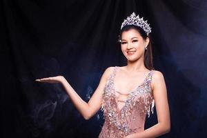 portrait du concours de beauté miss pageant en robe de soirée à sequins roses avec couronne de diamants, femme asiatique pointe les vagues de la main à l'autre sur fond sombre espace de copie de fumée photo