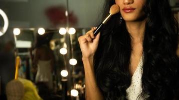 demi-corps désactiver personne sans doigts pouce main de jeune femme adulte à l'aide d'un pinceau cosmétique rouge à lèvres au bureau miroir de maquillage. Sourire féminin joyeux en robe de soirée blanche robe de bal cheveux longs photo