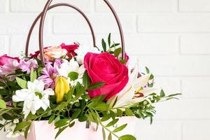 boîte rose avec bouquet de fleurs sur une table. merveilleuse composition de fleurs violettes, rouges, blanches avec de la verdure est un cadeau parfait pour un anniversaire ou un mariage photo