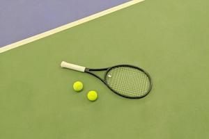 vue de dessus de la raquette de tennis et de deux balles sur le court de tennis en terre battue verte photo