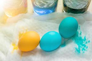 processus de mort des oeufs de pâques. tasses en verre transparent avec de l'eau colorée et des œufs colorés, vue de dessus photo