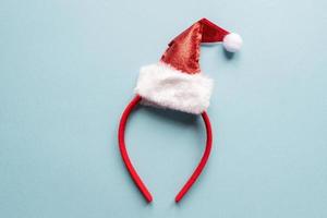 bande de cheveux avec bonnet de noel sur fond bleu. coiffure de noël festive pour animaux ou enfants photo