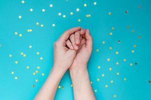 mains féminines avec manucure nue sur fond bleu avec des étoiles dorées dispersées. fond festif. notion de naturalité. photo