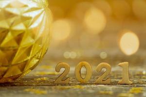 2021 chiffres en bois sur fond bokeh aux couleurs dorées. carte de voeux festive pour le nouvel an avec espace de copie. photo