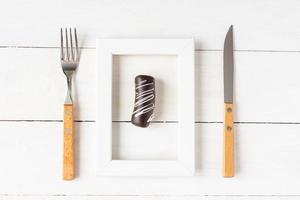 concept d'aliments et de régimes alimentaires sains. petit dessert dans un cadre photo servi avec fourchette et couteau sur tableau blanc
