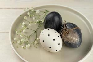 Oeufs de pâques gris teints naturels dans une assiette sur fond de bois rustique. point de vue en plongée. photo