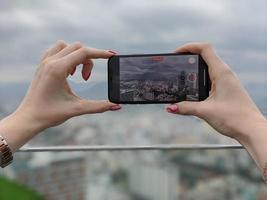 femme prenant une vidéo de la ville de nha trang, province de khanh hoa, viet nam avec un smatphone moderne. photo