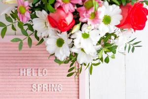 citation - bonjour le printemps. cadre de bordure fait de fleurs épanouies sur fond blanc photo