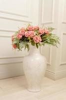 bouquet de roses roses dans un vase en céramique au sol dans un style classique. décoration d'intérieur shabby chic. photo