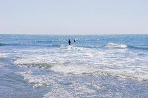 les gens surfent dans l'oean par une journée ensoleillée photo