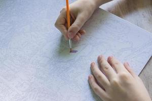 peinture sur toile par numéros. un enfant tient un pinceau et le dessine. passe-temps créatif. peinture pour débutants. photo