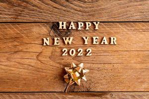 bonne année 2022 inscription faite avec des lettres en bois décorées d'arcs dorés festifs sur fond en bois avec espace de copie. carte de voeux pour la fête du nouvel an photo