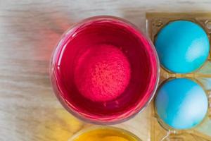 processus de mort des oeufs de pâques. tasses en verre transparent avec de l'eau colorée et des œufs colorés, vue de dessus photo