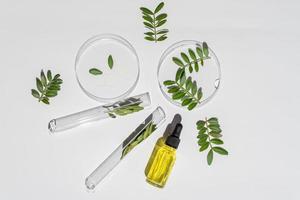 verrerie de laboratoire et flacon de pipette avec sérum et huile sur fond blanc. médecine naturelle, recherche cosmétique, sciences biologiques, produits de soins de la peau biologiques. concept de soins de la peau. photo