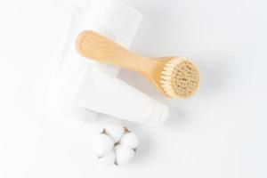 ensemble de spa pour les soins de la peau à domicile. crème en tube blanc, brosse en bois à poils naturels et serviette en coton blanc. concept de soins personnels photo