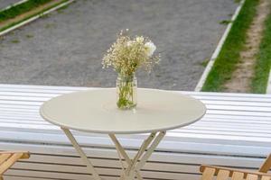café de la rue. chaises en bois et table ronde en métal avec bouquet de fleurs par une journée ensoleillée. photo