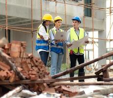 une ingénieure en construction tient une réunion d'ordinateur portable avec un travail d'équipe d'architecte. un groupe de personnes multiraciales porte un casque de sécurité à l'aide d'un ordinateur portable remue-méninges sur le développement du logement sur le chantier de construction photo