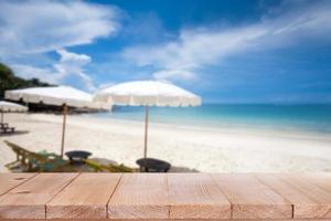 dessus de table en bois sur la mer bleue floue et fond de plage de sable blanc photo