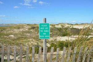Clôture en bois et dunes de sable à la plage avec s'il vous plaît rester à l'écart photo