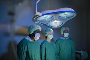 groupe de chirurgiens professionnels métis opérant dans la salle d'opération de l'hôpital, concept de soins de santé. photo