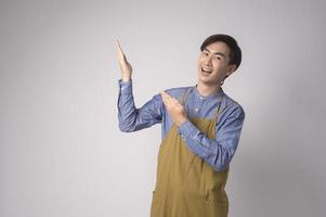 portrait de jeune homme asiatique portant un tablier sur fond blanc studio, cuisine et concept d'entrepreneur photo