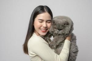 une jeune femme tient un joli chat, jouant avec un chat en studio sur fond blanc photo