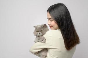 une jeune femme tient un joli chat, jouant avec un chat en studio sur fond blanc photo