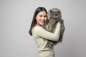 une jeune femme tient un joli chat, jouant avec un chat en studio sur fond blanc photo