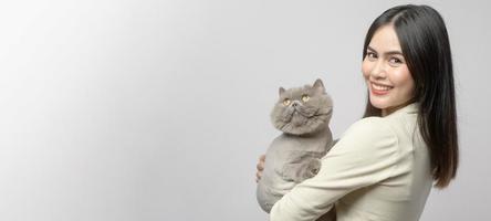 une jeune femme tient un joli chat, jouant avec un chat en studio sur fond blanc photo