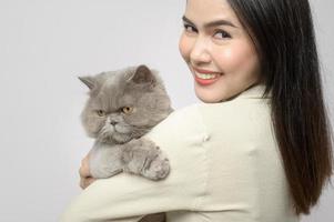 une jeune femme tient un joli chat, jouant avec un chat en studio sur fond blanc photo