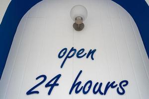 libellé de couleur bleue ouvert 24 heures sur 24 sur le mur blanc. photo