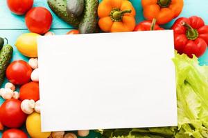 papier de recette avec des légumes sur une table bleue. vue de dessus photo