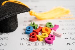 nombre mathématique coloré avec chapeau de graduation et crayon sur fond de feuille de réponses, étude de l'éducation apprentissage des mathématiques concept d'enseignement. photo