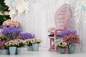 chaise en bambou vintage de luxe devant un fond en bois blanc et de nombreuses fleurs autour. photo