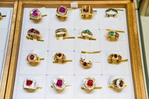 de nombreux bijoux de type bague gemme sont disposés sur la plaque dorée dans le magasin de bijoux de la boîte à miroir. photo
