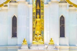 statue de bouddha en or blanc assis trois or debout devant le bâtiment blanc. photo