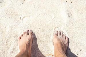 2 pieds sur l'eau de Javel. gros plan de pieds de jeune homme sur une plage de sable tropicale. photo