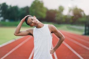 athlètes sport homme coureur portant des vêtements de sport blancs pour s'étirer et se réchauffer avant de s'entraîner sur une piste de course dans un stade. concept de sport de coureur. photo