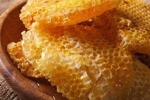 nid d'abeille doré frais sur macro de plaque de bois. horizontal