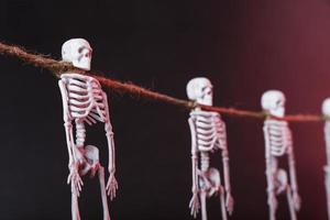 crânes de squelettes suspendus par le cou sur une corde sur fond sombre. photo