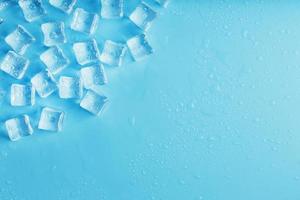 glace faite de cubes alignés avec des gouttes sur fond bleu avec espace libre photo