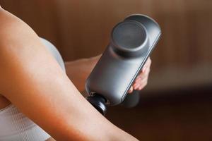 auto-massage des mains des femmes à l'aide d'un pistolet à percussion à la maison. photo