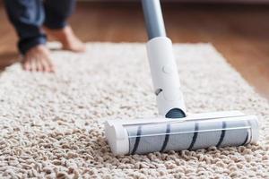 une brosse turbo blanche d'un aspirateur sans fil sur le tapis. concept de nettoyage intérieur photo