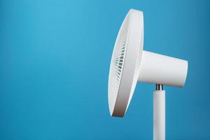 ventilateur électrique moderne blanc pour refroidir la pièce sur fond bleu. photo