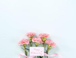 fond de fête des mères, bouquet d'oeillets - beau bouquet de fleurs rose pâle isolé sur une table bleu pastel, vue de dessus, mise à plat, conception d'espace de copie. photo