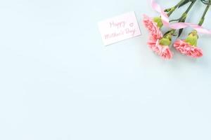 fond de fête des mères, bouquet d'oeillets - beau bouquet de fleurs rose pâle isolé sur une table bleu pastel, vue de dessus, mise à plat, conception d'espace de copie. photo