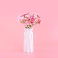 concept de conception de cadeau de fête des mères, bouquet de fleurs d'oeillets roses avec carte de voeux, isolé sur fond rose clair, espace de copie. photo