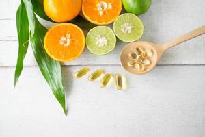 multivitamines et suppléments dans une cuillère en bois avec des fruits frais sur fond de bois blanc. photo