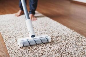 une brosse turbo blanche d'un aspirateur sans fil sur le tapis. concept de nettoyage intérieur photo