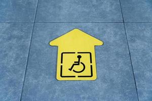 un dessin d'un fauteuil roulant sur une flèche jaune collée sur le carrelage de la salle d'attente photo